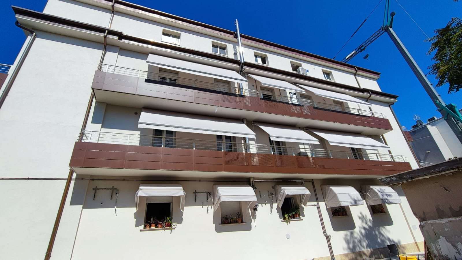 Condominio con cappottine alle finestre e tende sui balconi