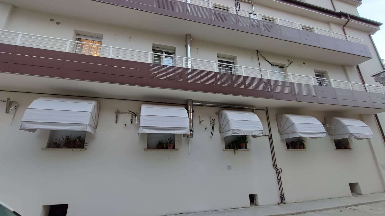 Fila di cappottine bianche sulle finestre di un edificio