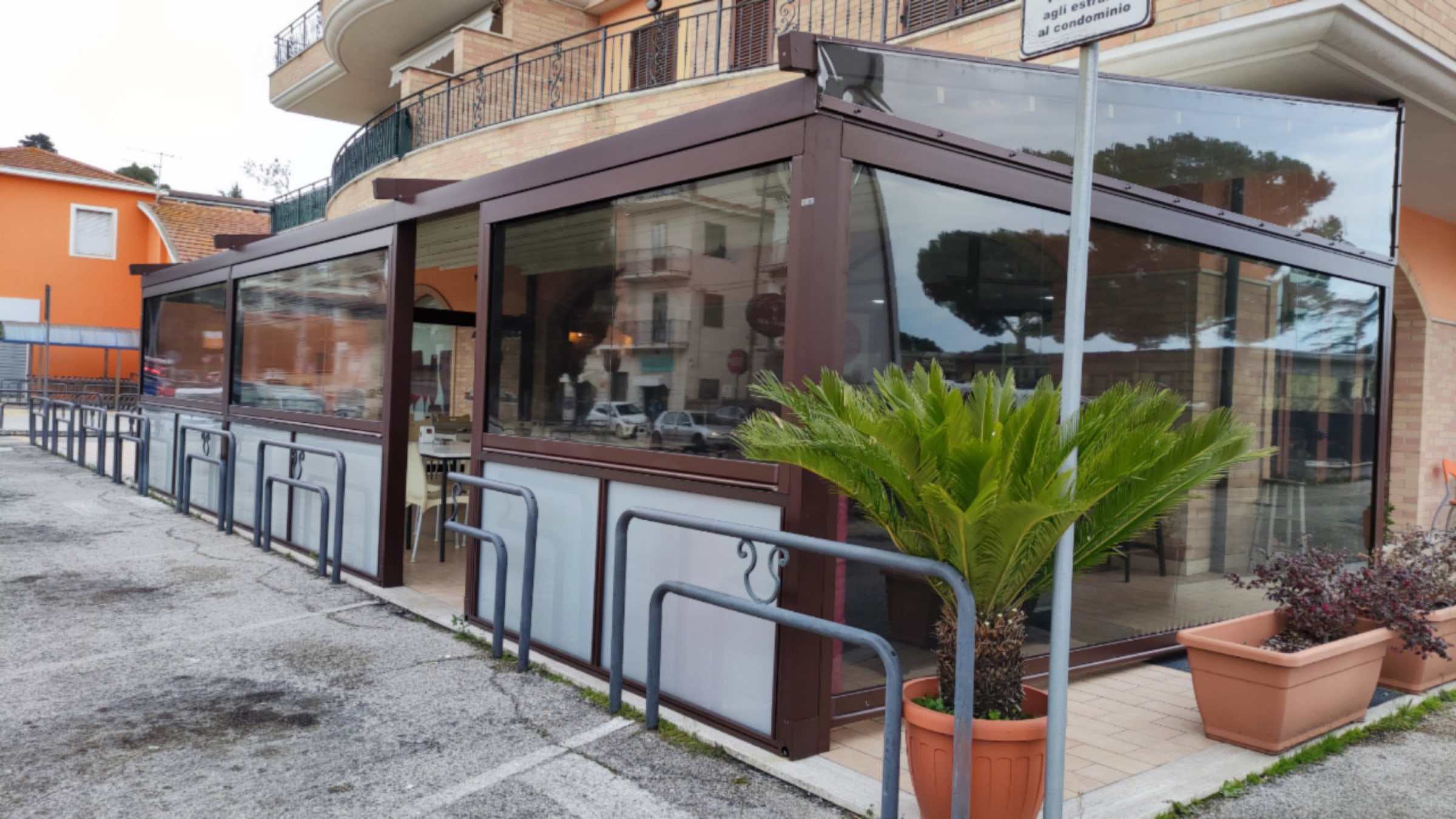 Dehors di un bar con pergotenda marrone e chiusure laterali trasparenti