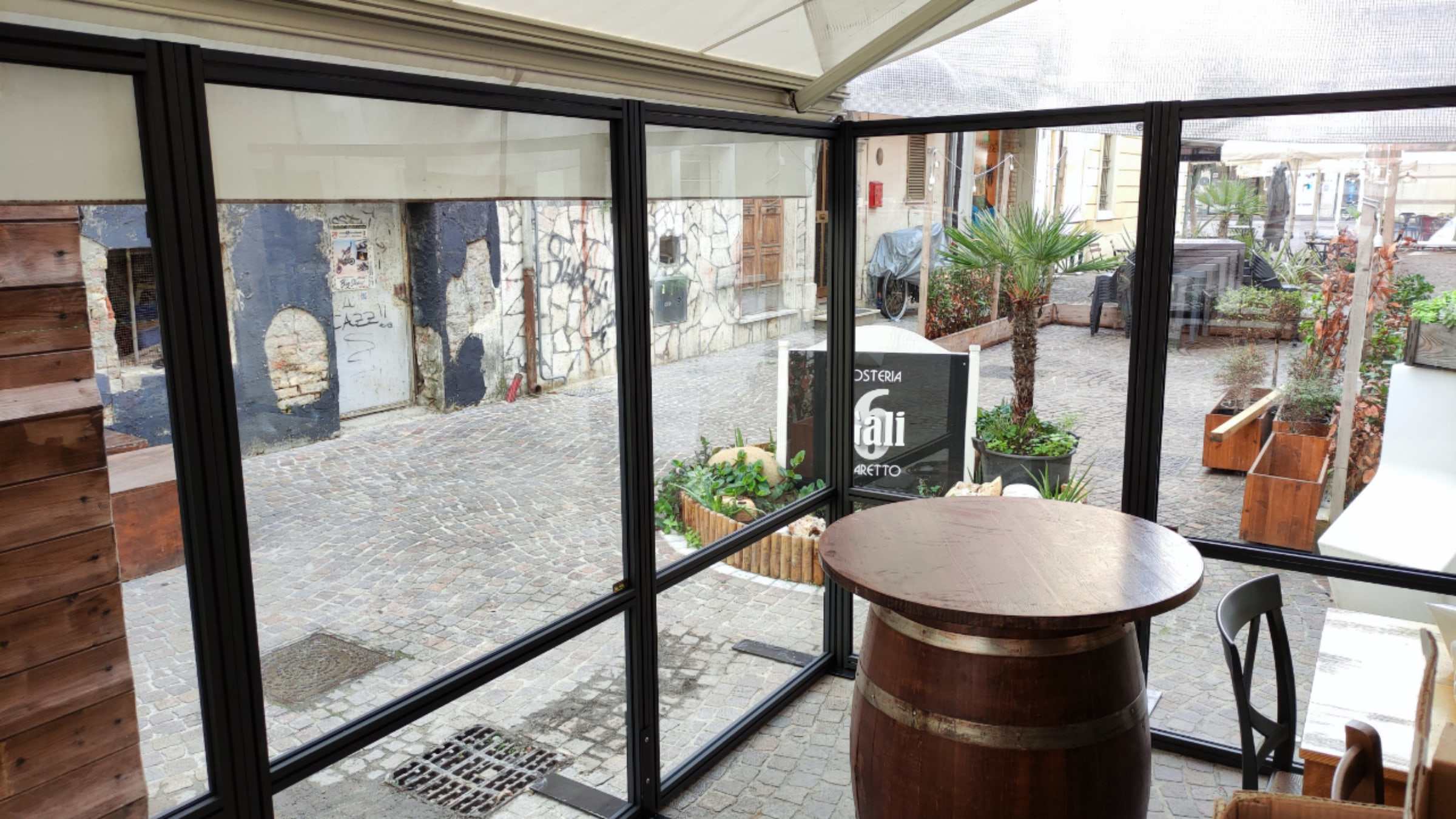 Dehors di un'osteria chiuso da pannelli trasparenti con telaio scuro