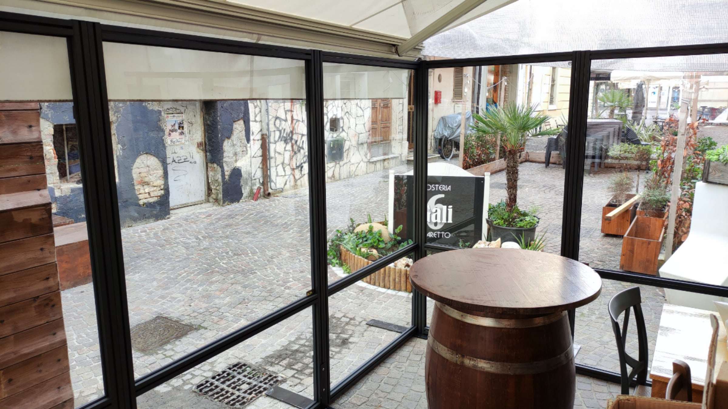Dehors di un'osteria chiuso da pannelli trasparenti con telaio scuro