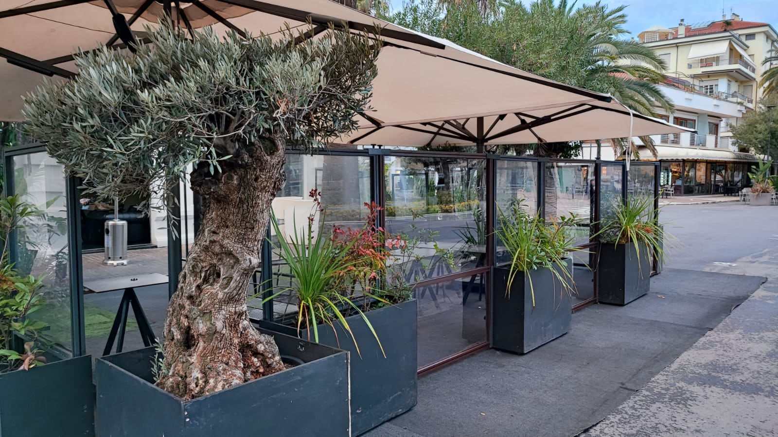 Dehors con paraventi in vetro, fioriere e ombrelloni