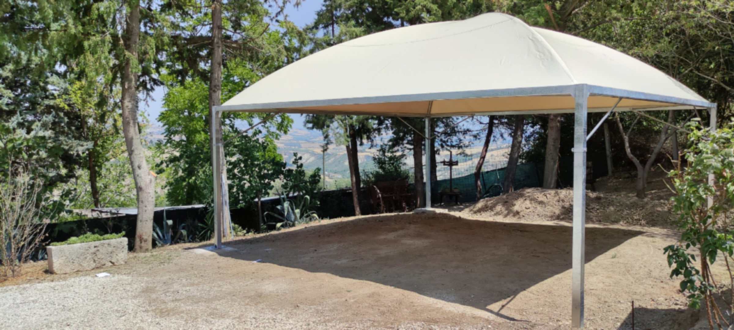 Gazebo bianco su terreno in collina tra gli alberi