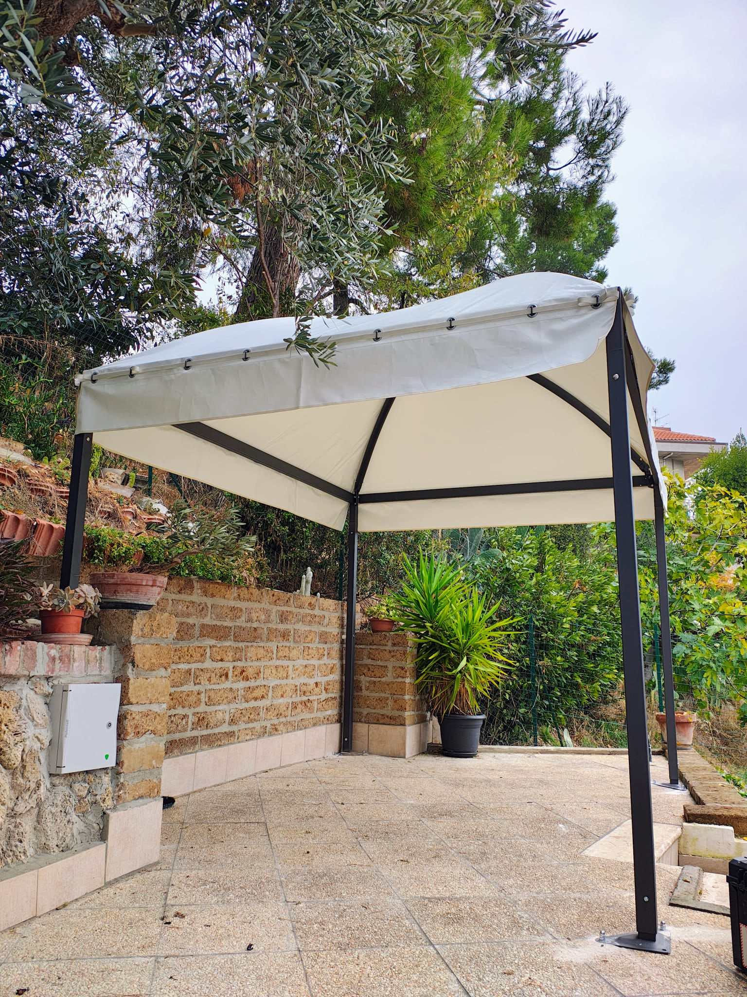 Gazebo bianco su terrazzo con muro in pietra
