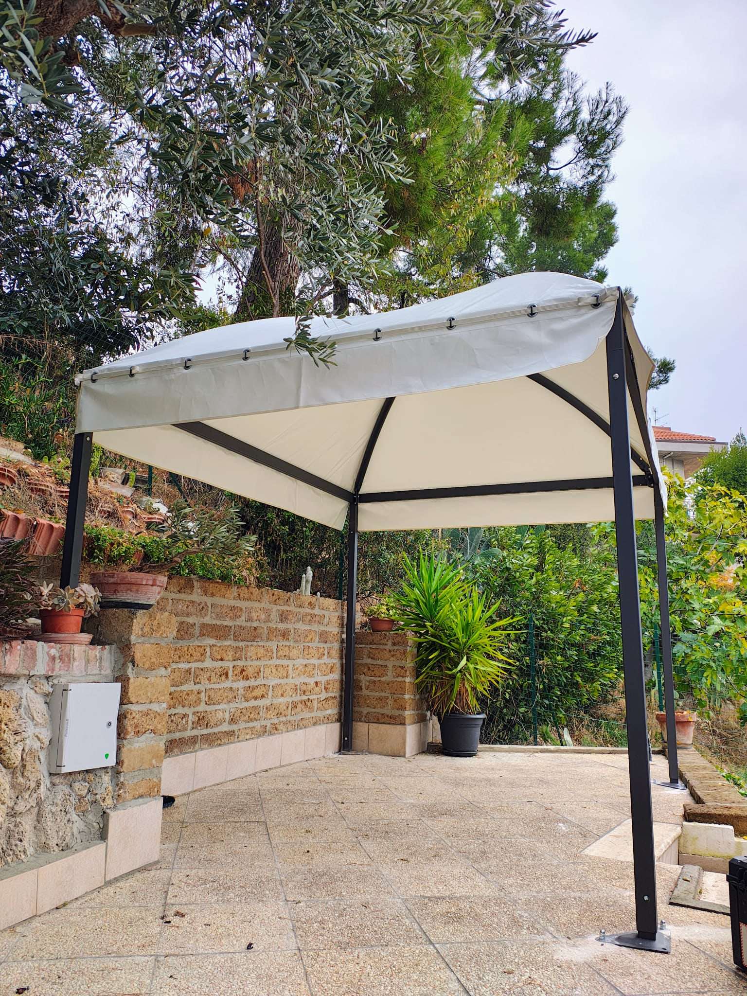 Gazebo bianco su terrazzo con muro in pietra