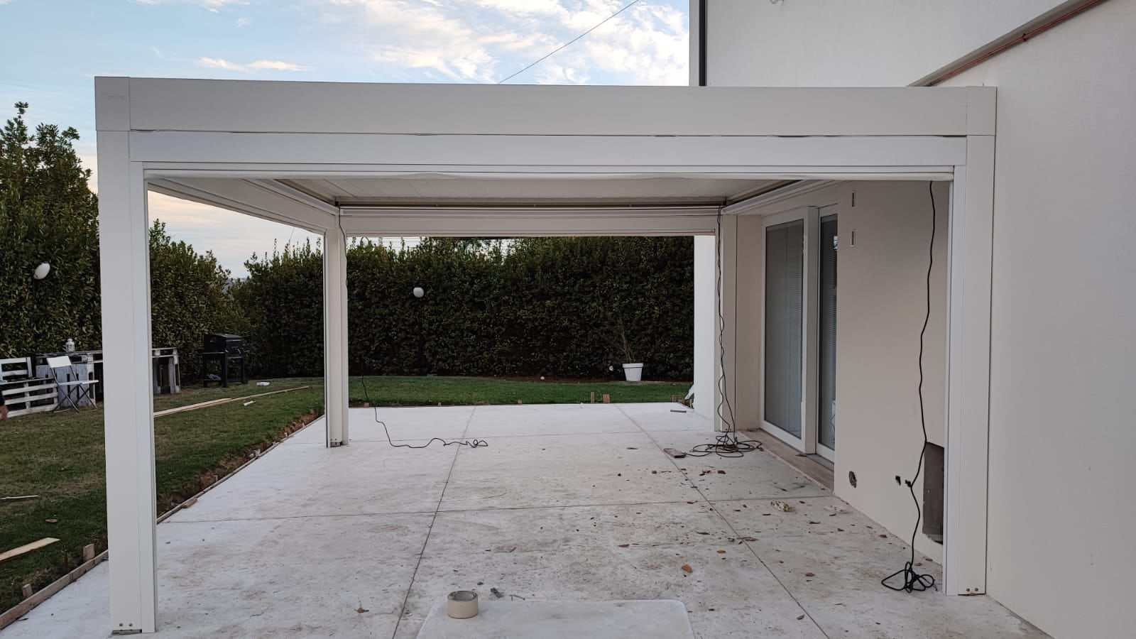 Pergola bioclimatica bianca su patio affacciato al giardino