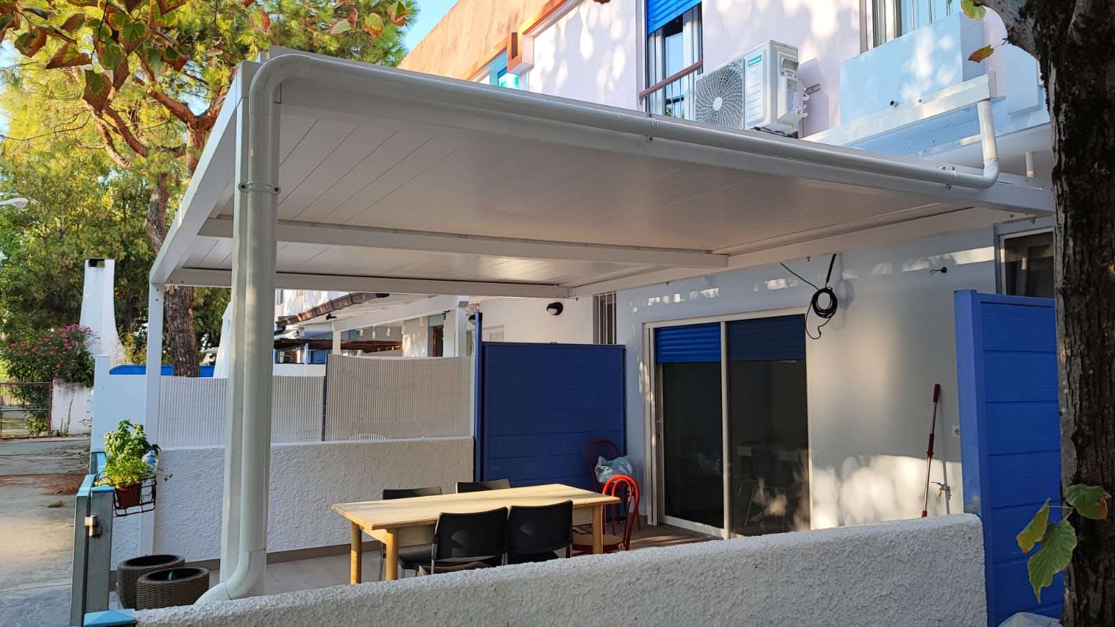 La stessa pergola bioclimatica con le lamelle chiuse sopra il tavolo da pranzo
