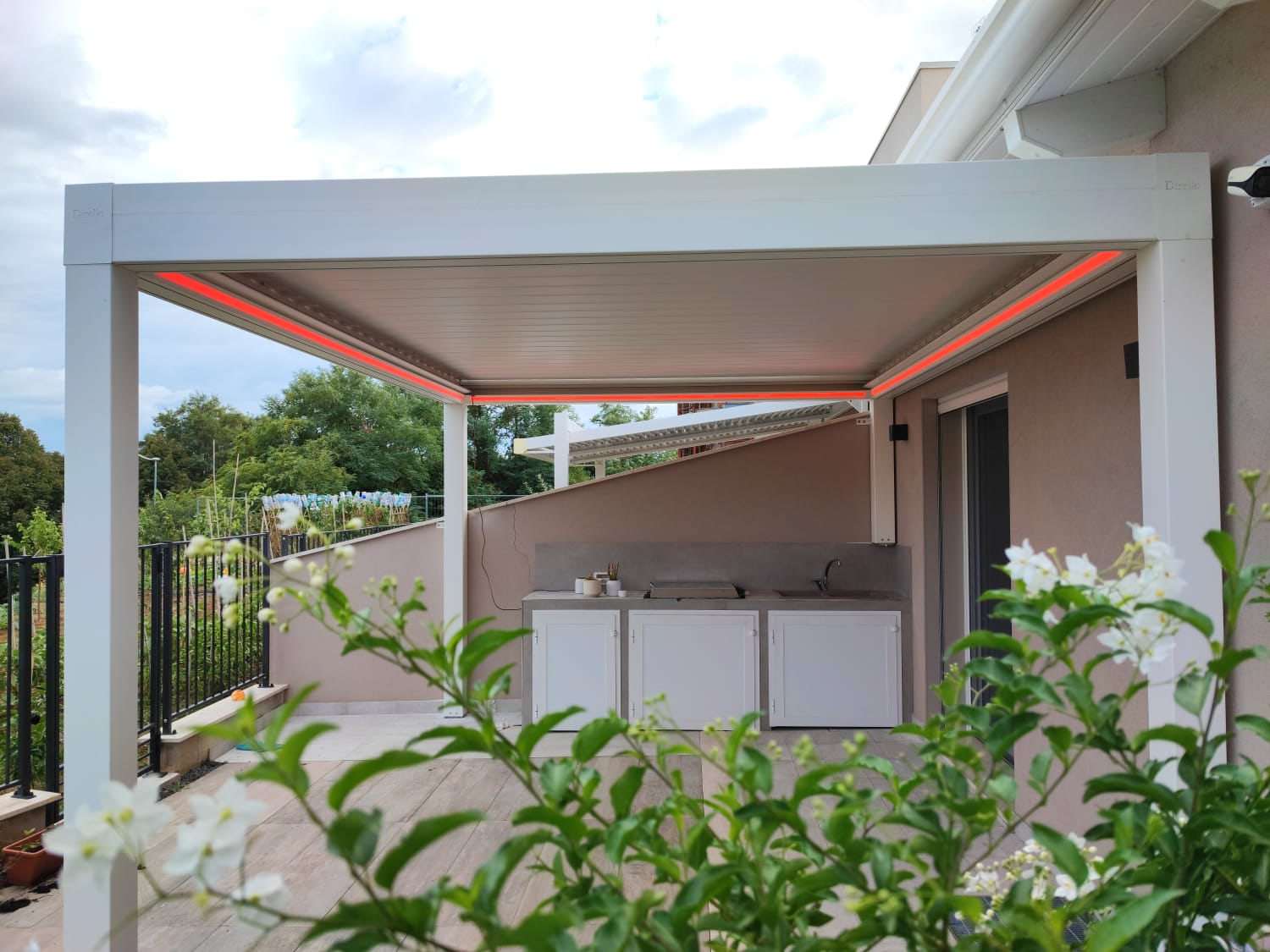 Pergola bioclimatica con luce LED sopra una cucina da esterno