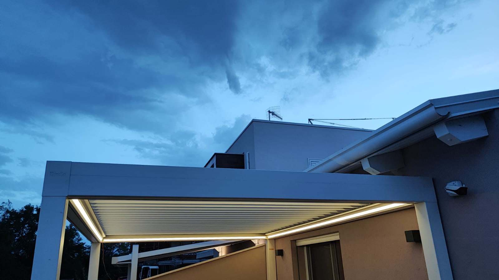 Pergola bioclimatica con LED integrati accesi al tramonto