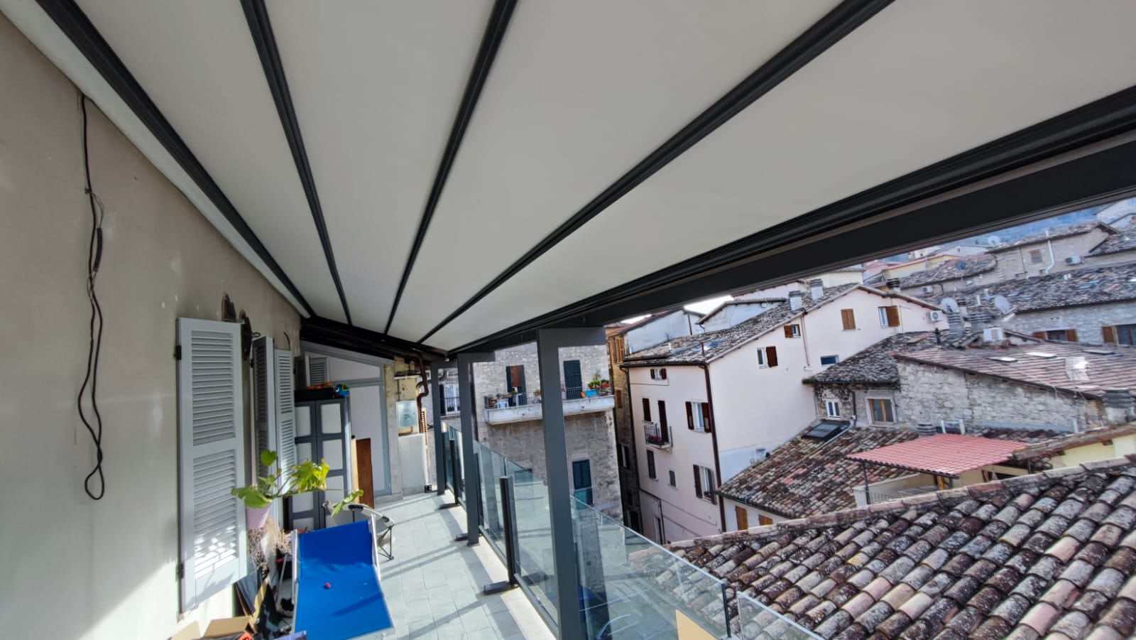 Pergotenda antracite su balcone affacciato sui tetti di un borgo storico