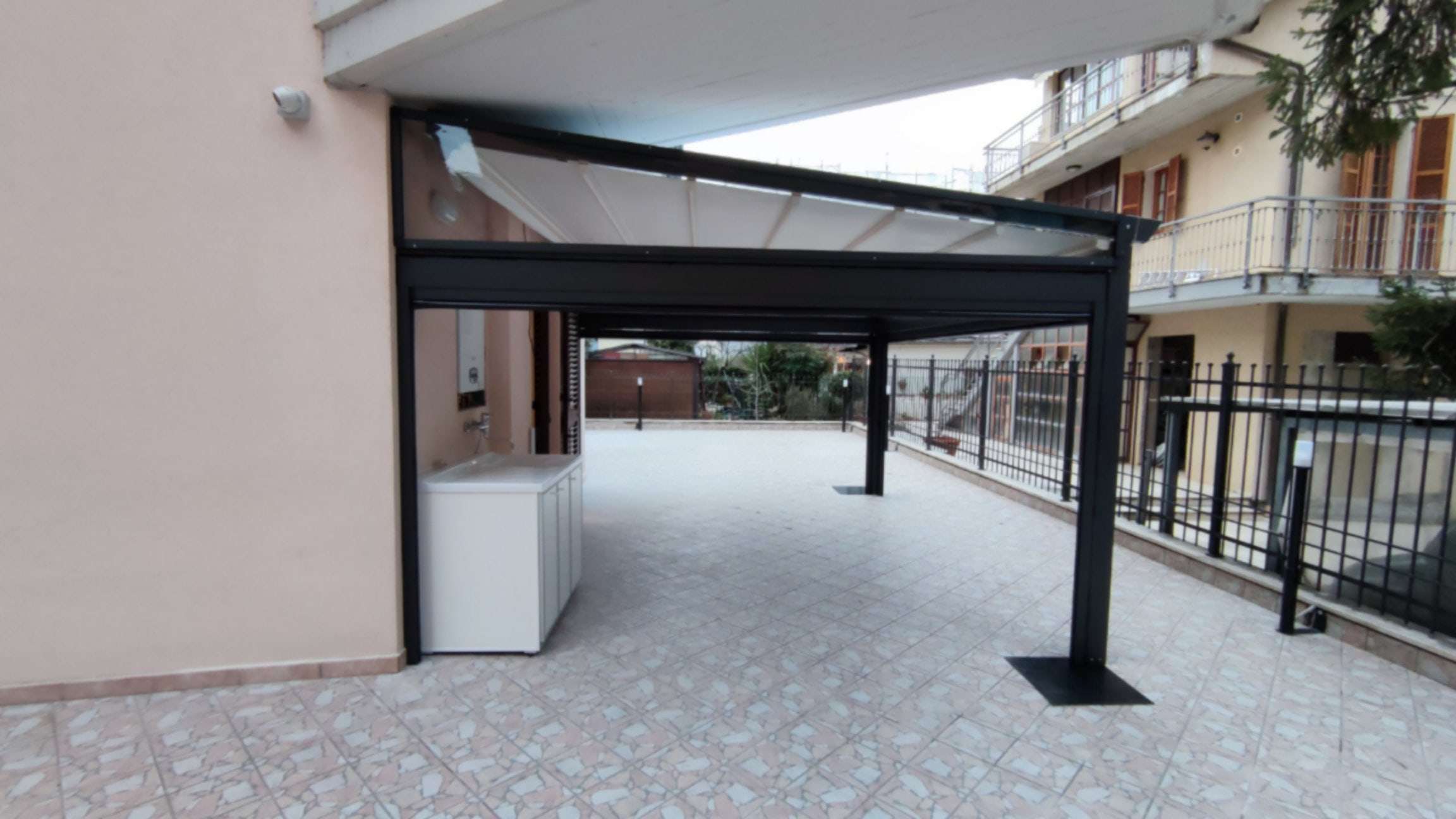 Struttura antracite di una pergotenda con telo bianco su terrazzo pavimentato