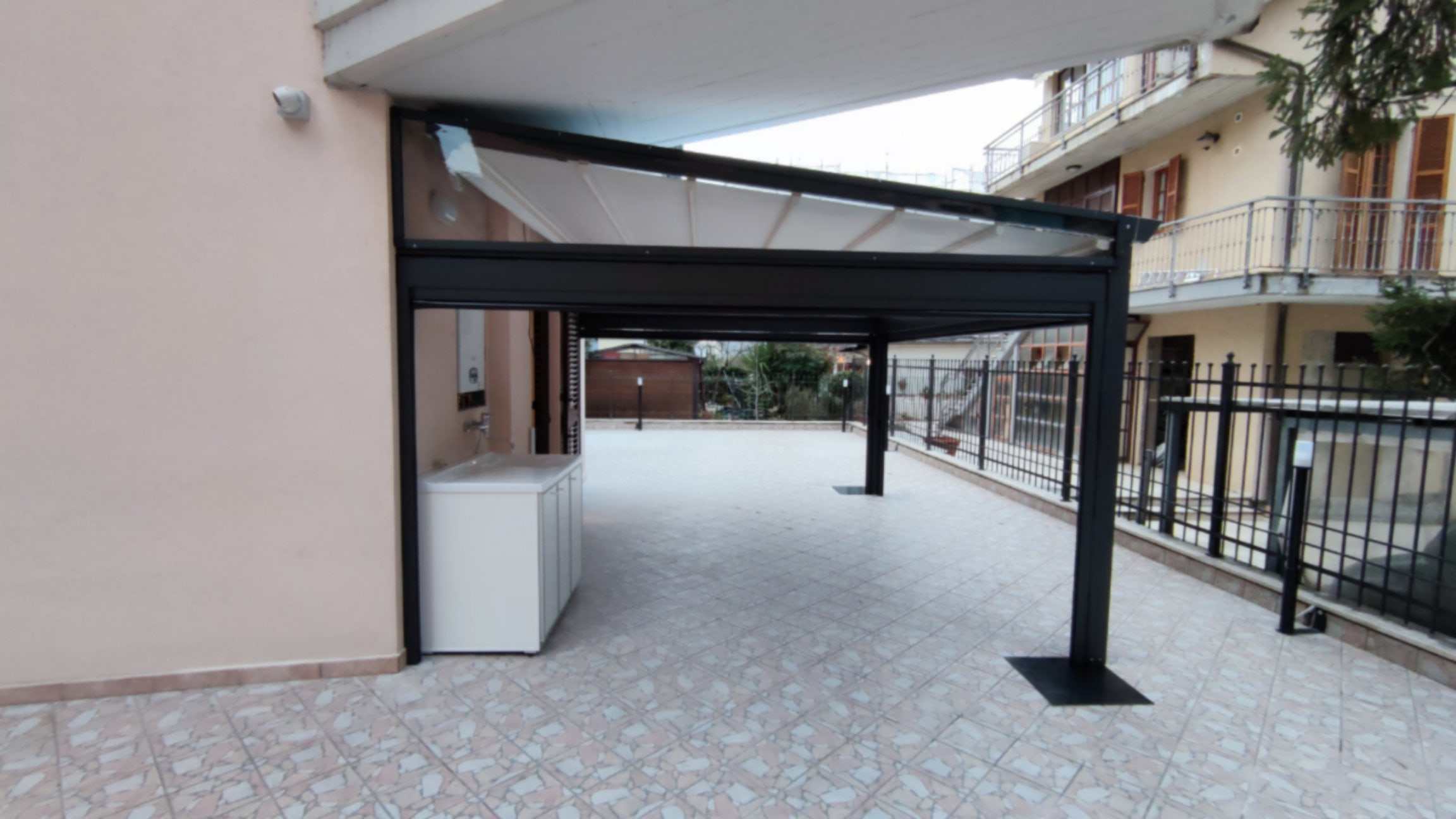 Struttura antracite di una pergotenda con telo bianco su terrazzo pavimentato
