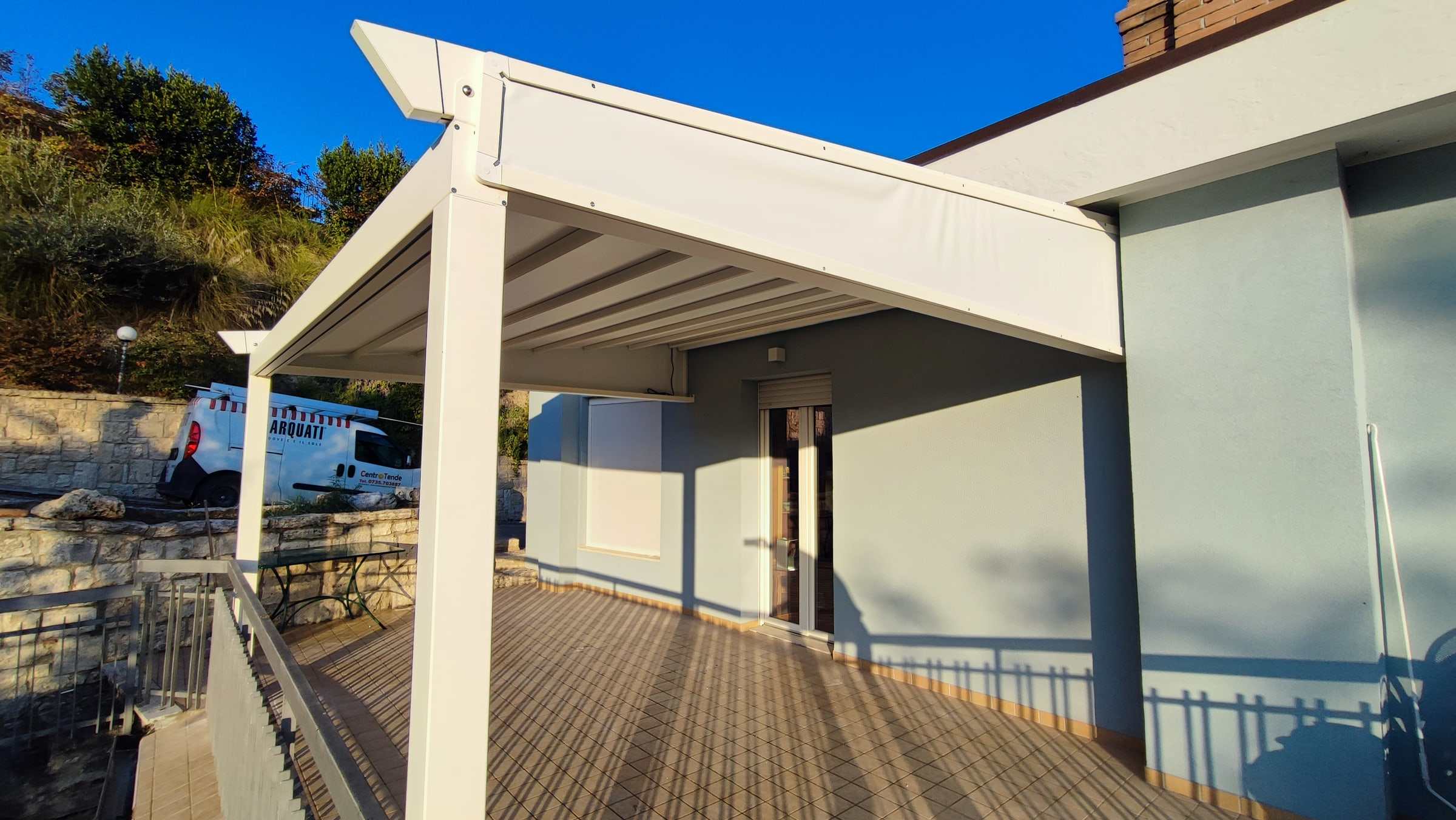Pergotenda bianca su un terrazzo con pavimento in legno
