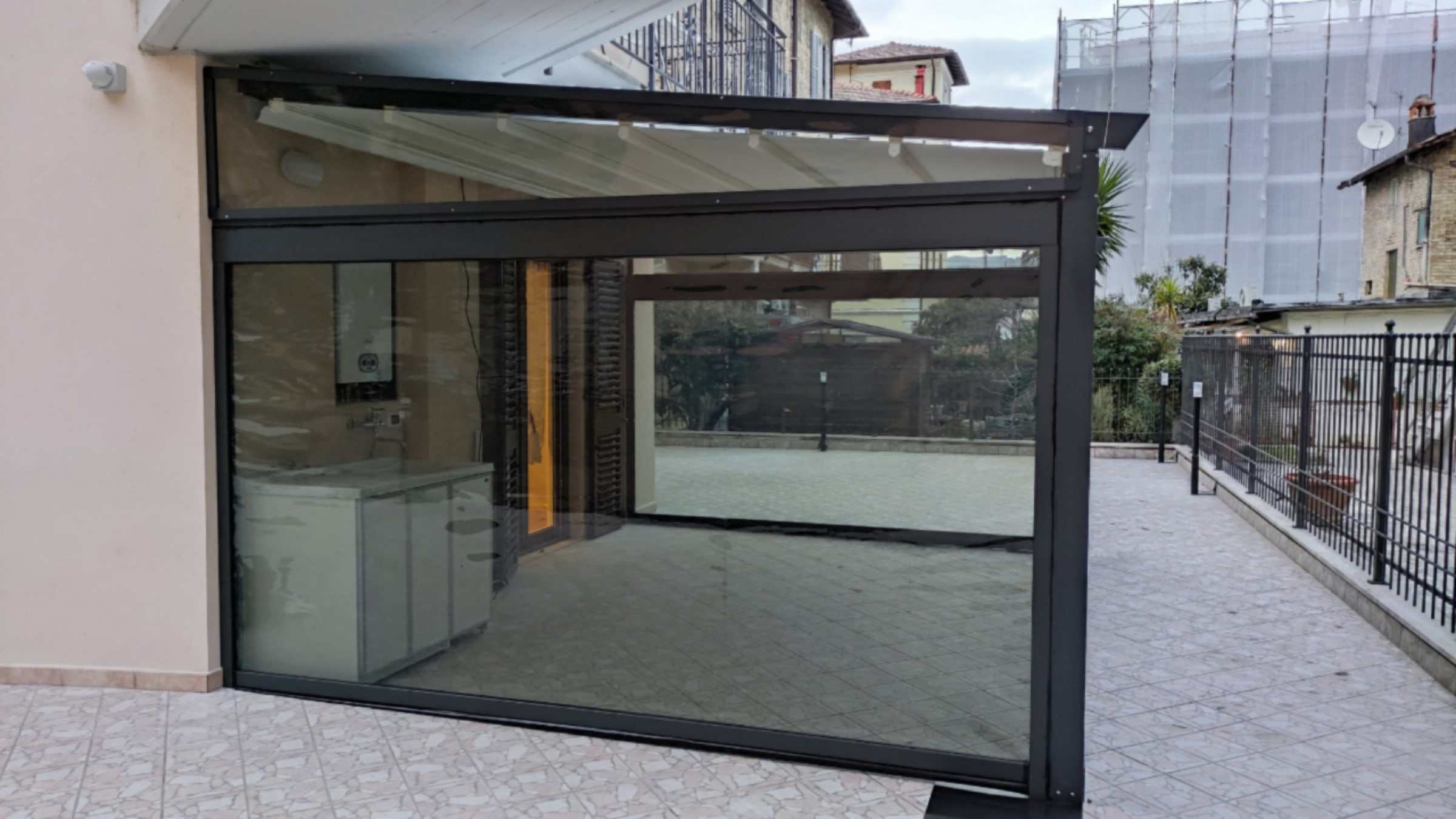 Pergotenda antracite chiusa su tre lati da vetrate scorrevoli su un terrazzo