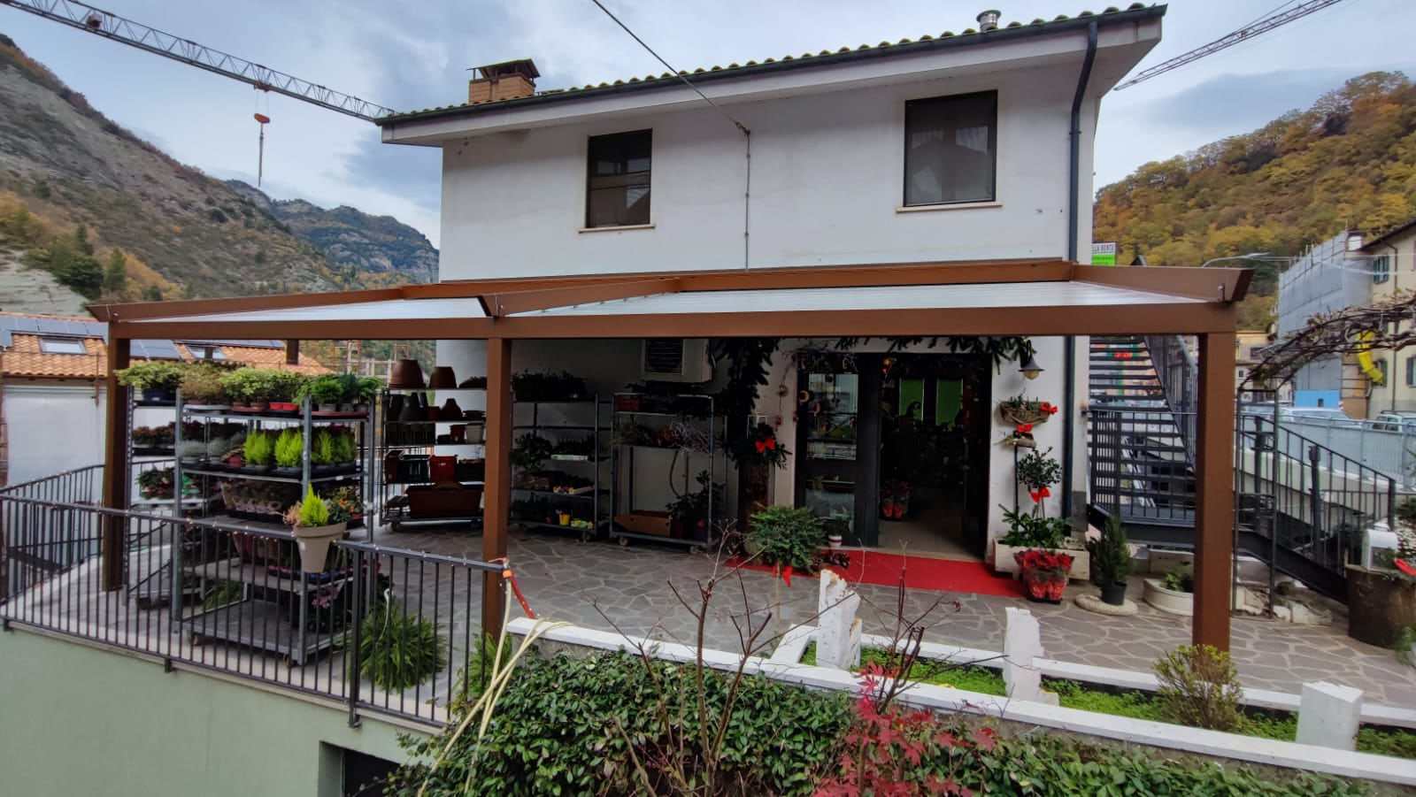 Pergotenda color legno davanti a un negozio di piante in montagna