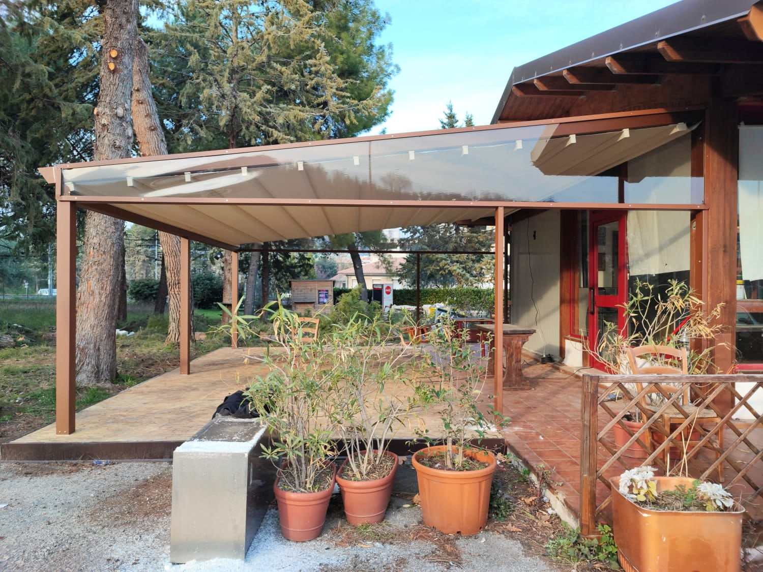 Pergotenda marrone sull'area esterna di un locale con giardino