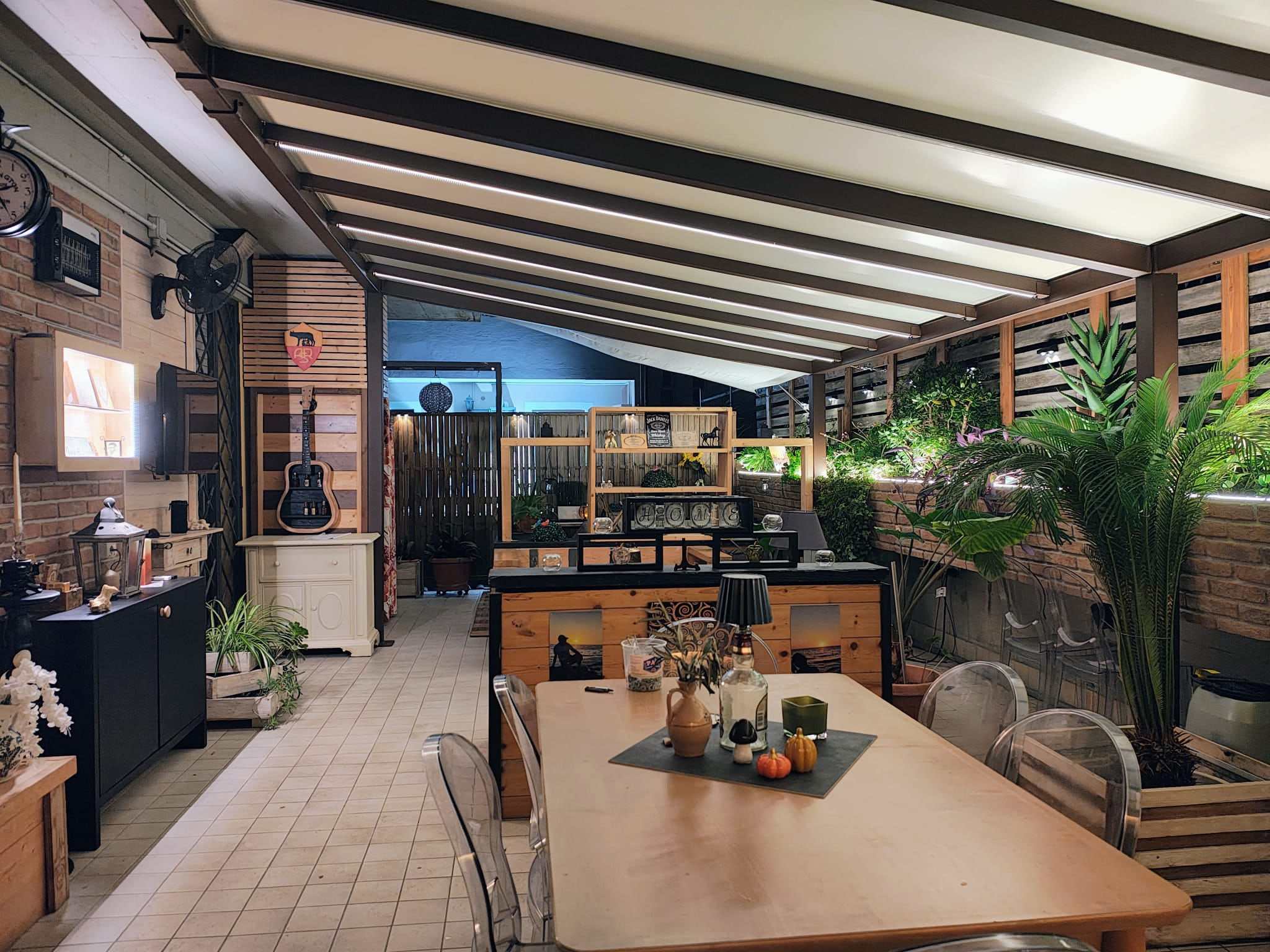 Patio arredato con tavolo da pranzo sotto una pergotenda, con luci serali