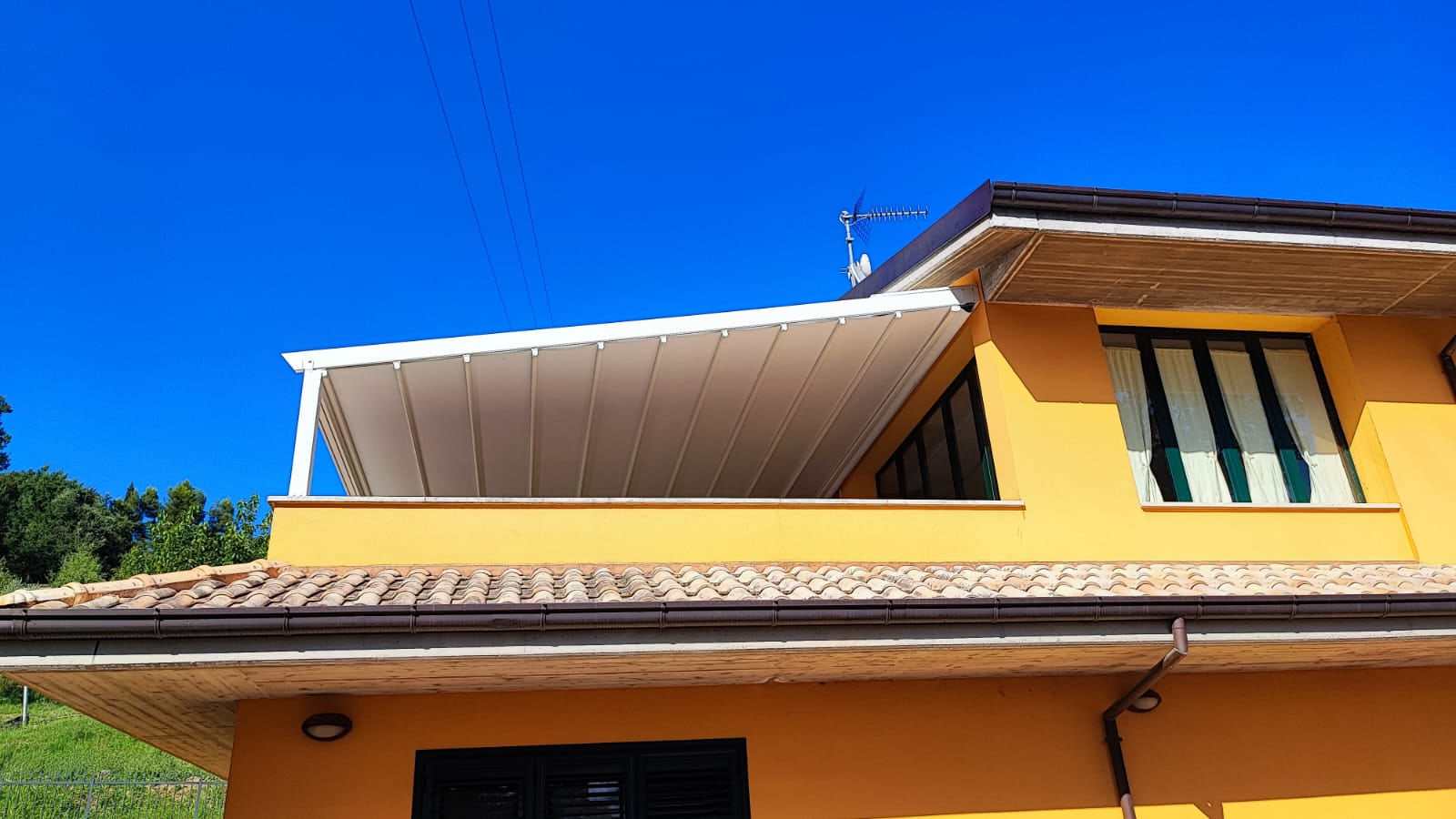 Pergotenda su terrazzo di una casa gialla sotto il cielo blu