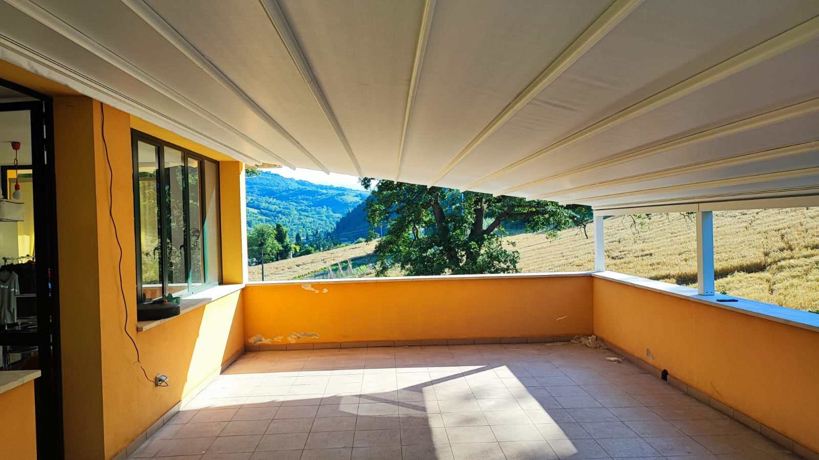 Terrazzo coperto da pergotenda con vista sul paesaggio collinare