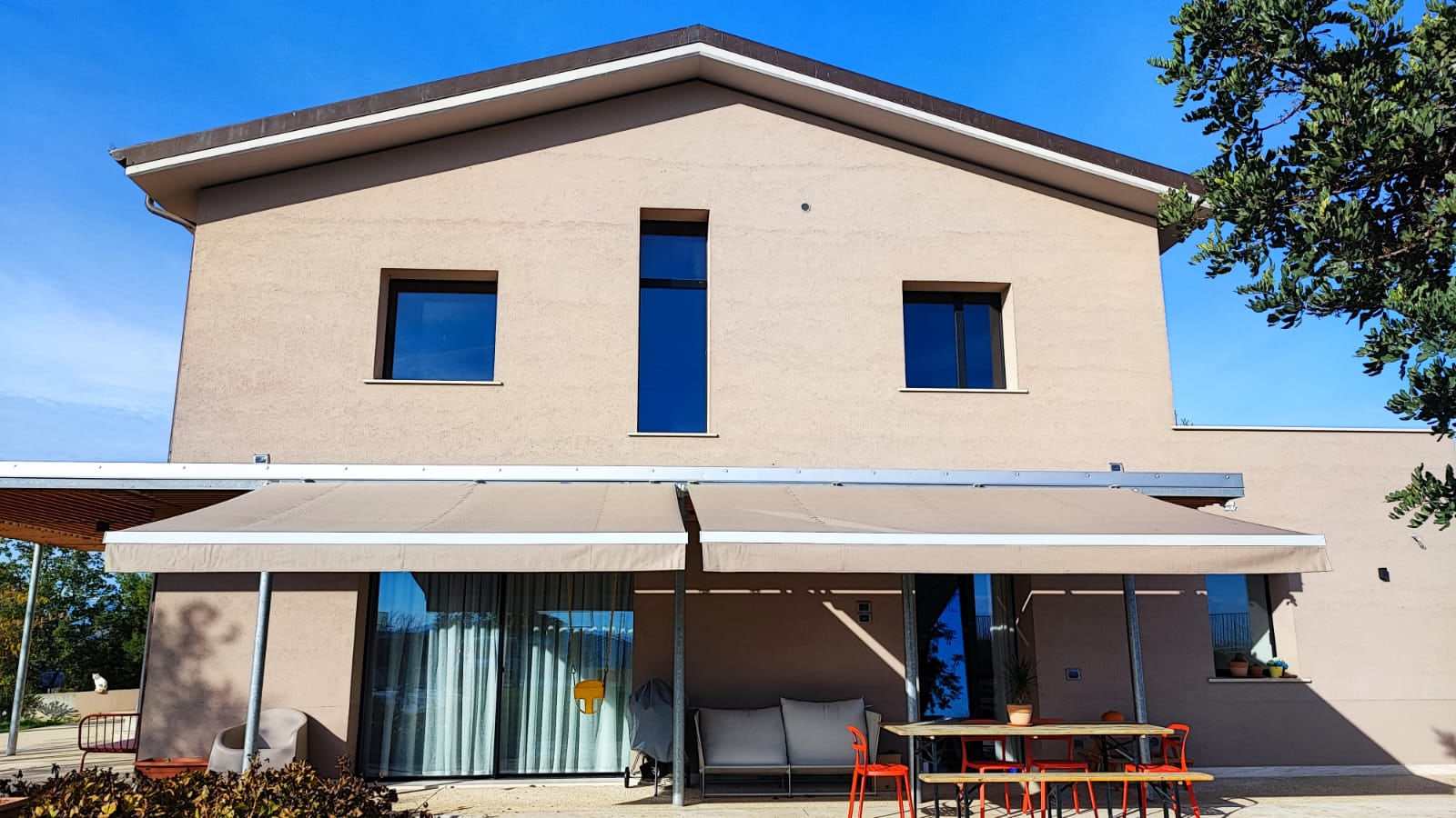 Tenda a bracci su villa moderna con tavolo all'aperto