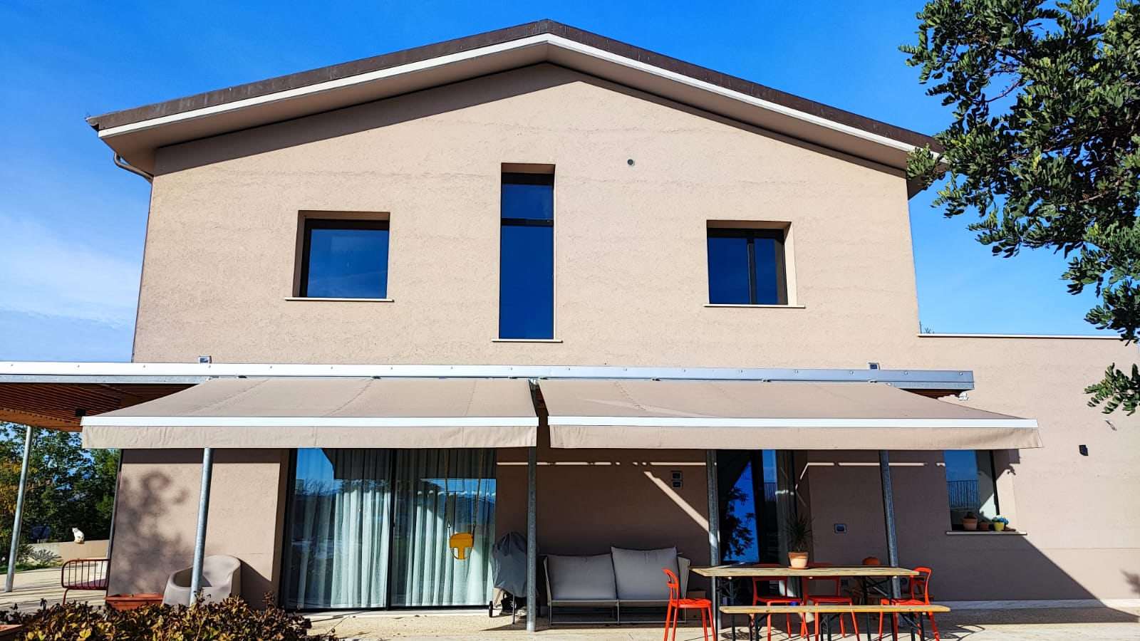 Tenda a bracci su villa moderna con tavolo all'aperto