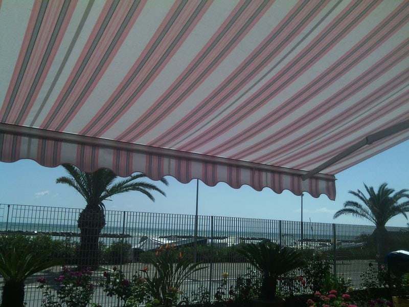 Tenda da sole a righe con vista sul mare e palme