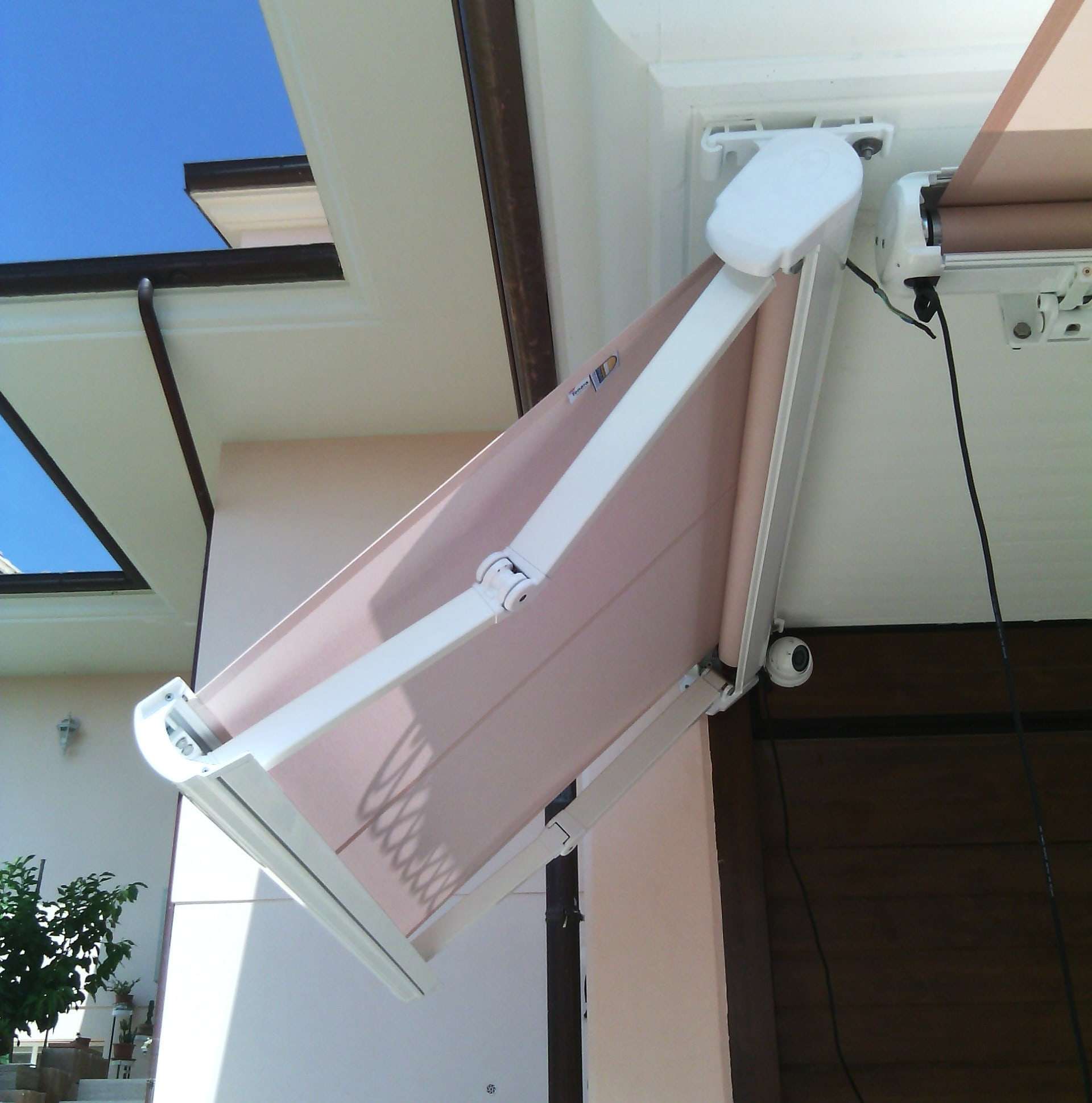 Tenda a caduta con braccetti e cassonetto bianco, motorizzata, con telo rosa antico, vista dal basso