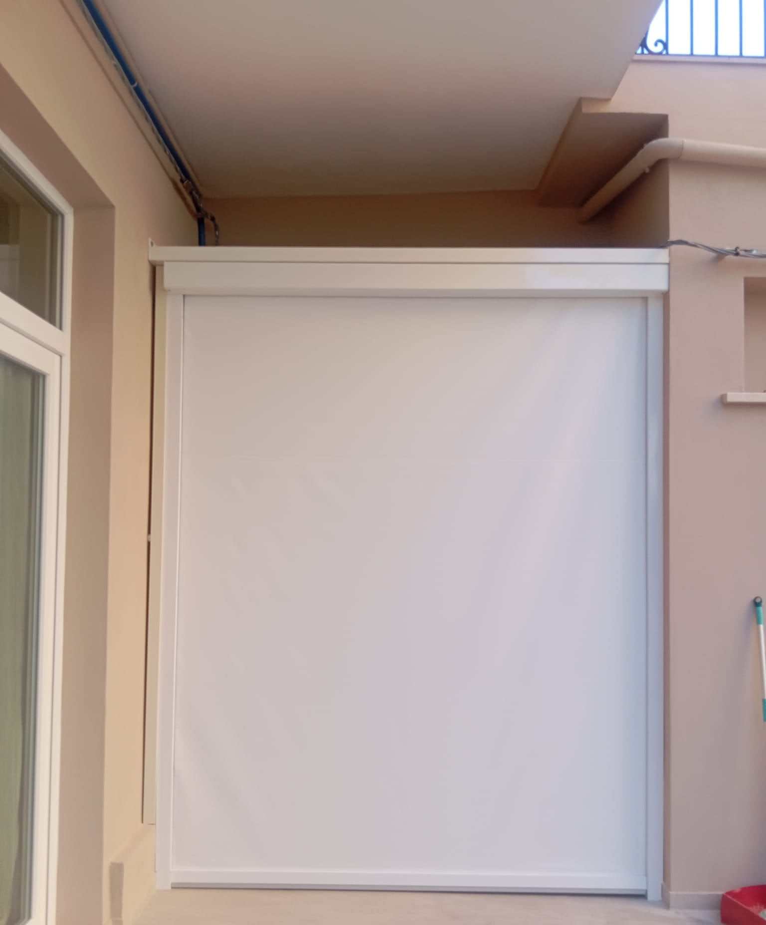 Tenda verticale con guide laterali che chiude un balcone