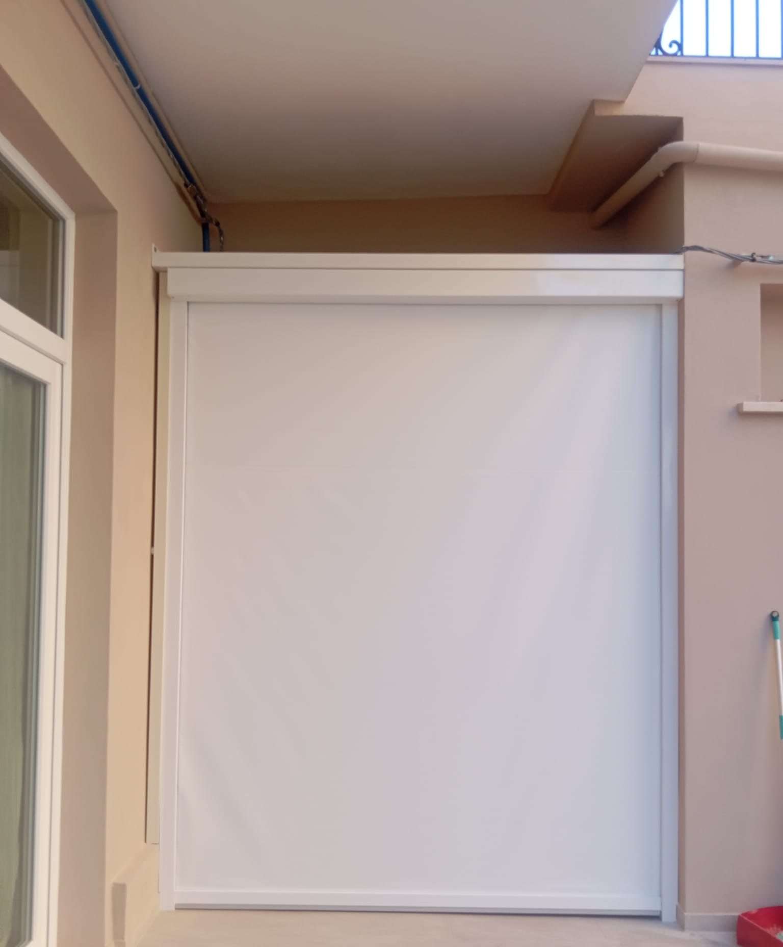 Tenda verticale con guide laterali che chiude un balcone