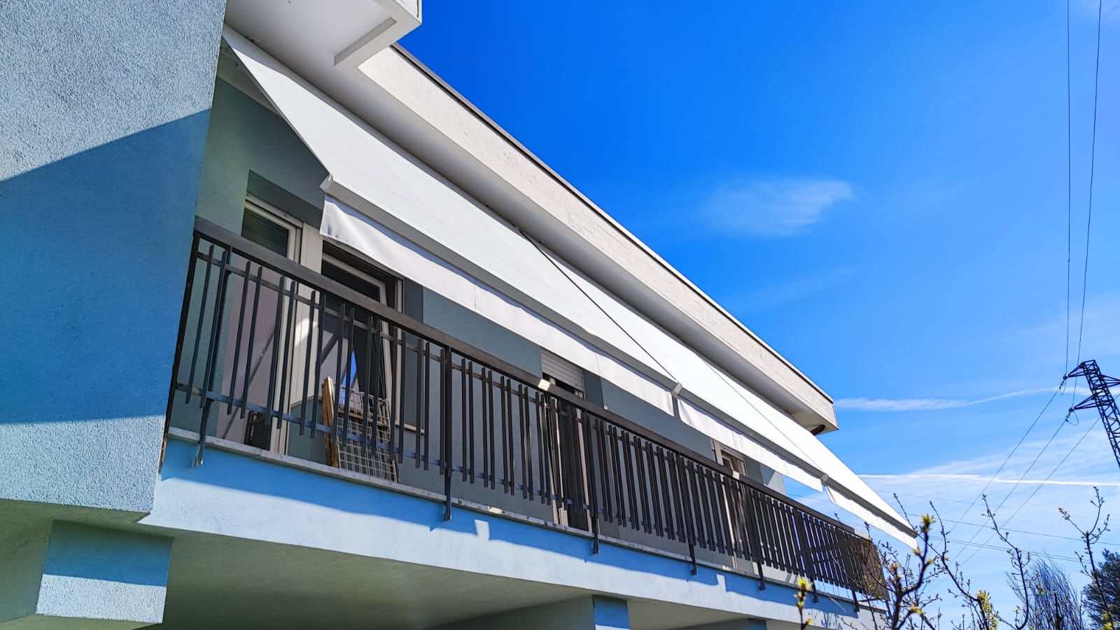 Tenda da sole sulla balconata di una casa azzurra