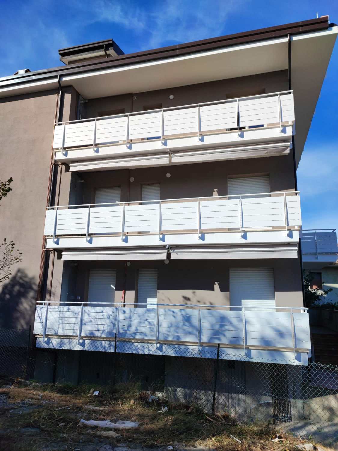 Palazzina con tende da sole chiuse sotto i balconi di tre piani