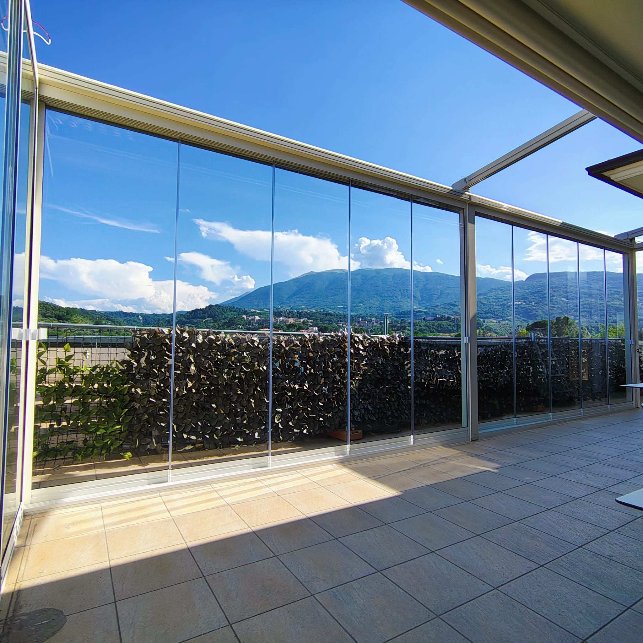 Terrazzo chiuso da vetrate scorrevoli trasparenti con vista sulla montagna